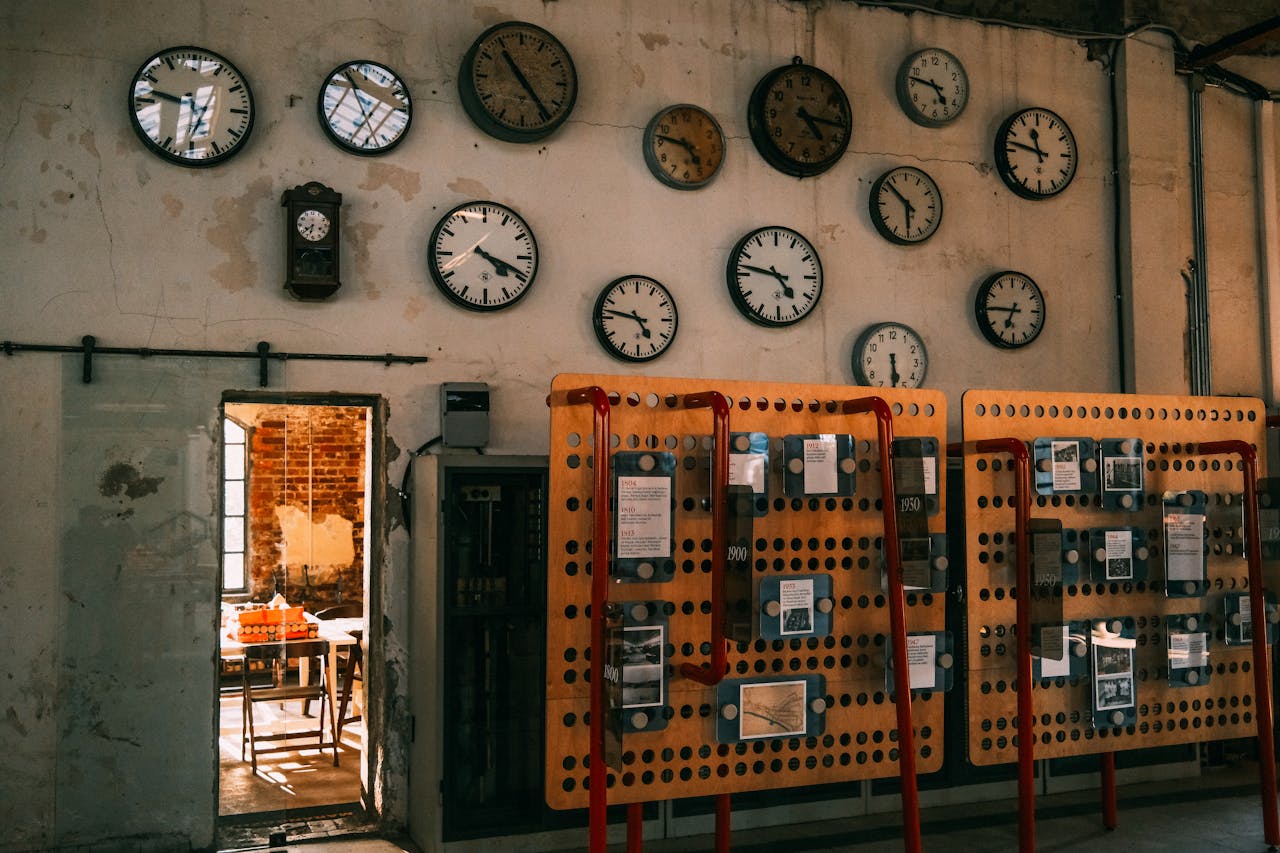 An array of vintage wall clocks in a dimly lit industrial setting, highlighting time and nostalgia.
